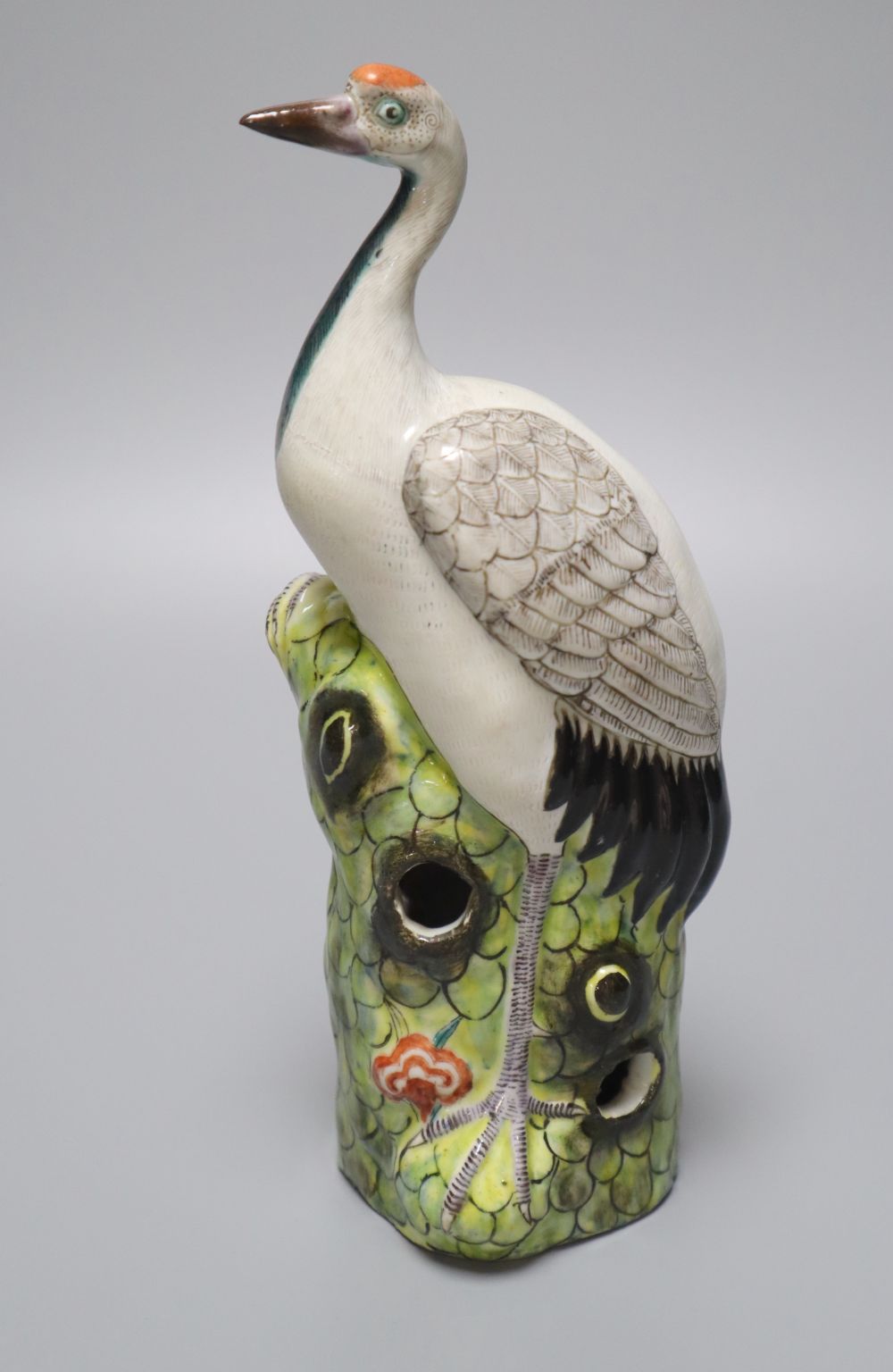 A Chinese enamelled porcelain model of a crane, 19th / 20th century, standing on a pine tree bough, height 24.5cm